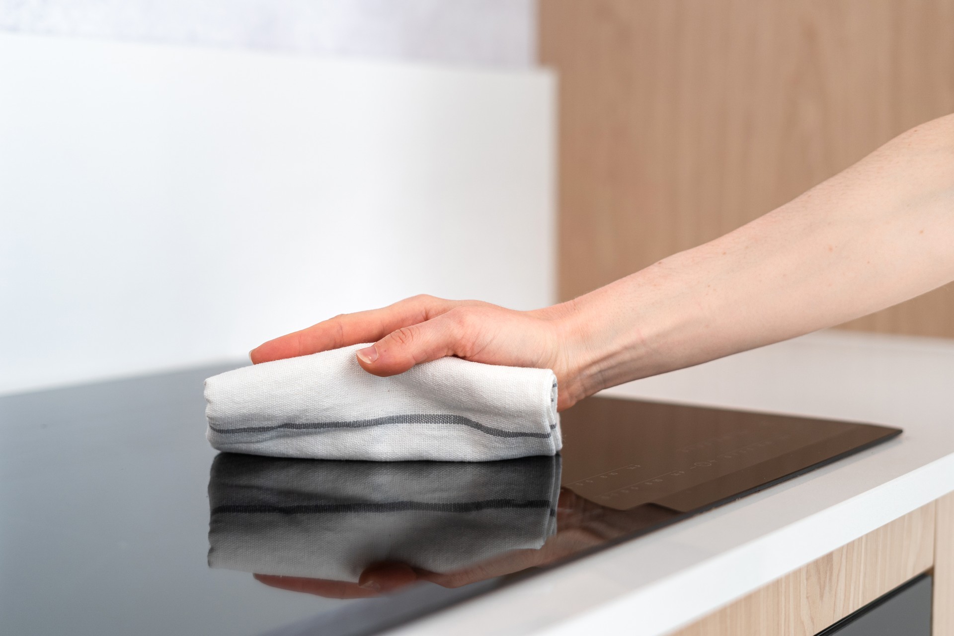 woman housewife wipe electrical cooker top with towel, closeup